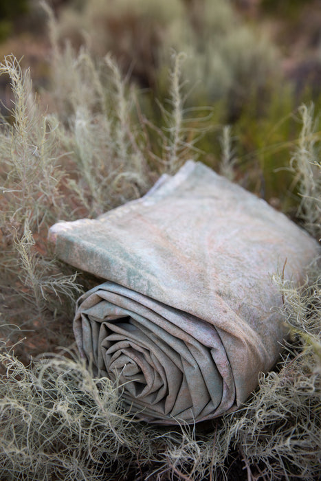 Ultraviolet Backdrops hand painted muslin Backdrop in a Bag rolls up to a small, lightweight bundle for easy travel and use. Here it sits on sage growing in the desert surrounded by the colors that inspired it.