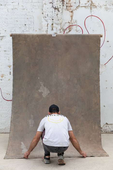 Man straightens hand painted backdrop in city