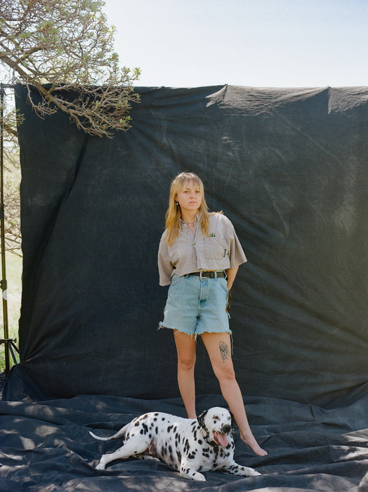 Blonde woman and dalmation stand on Ultraviolet Backdrops black muslin Backdrop in a Bag. Portable, lightweight, easy to use backdrop, huge muslin. Image shot by Logan Potterf on Kodak Gold 120 film.