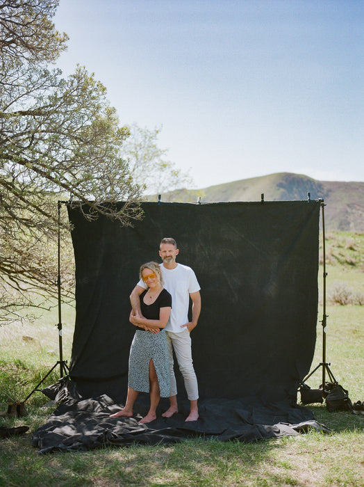 Ashley Thalman and Matthew Peterson of Ultraviolet Backdrops stand on their hand painted muslin Backdrop in a Bag. Image was shot on film by Logan Potterf.