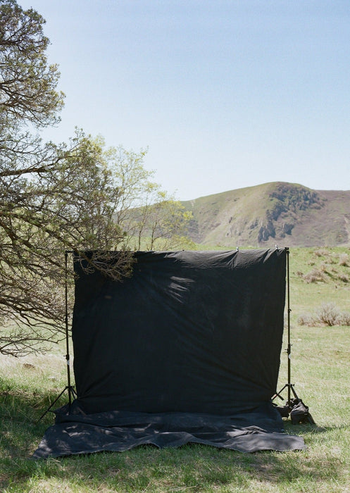 Huge, durable, muslin backdrop clipped to a traditional backdrop stand in the hills above Salt Lake City. Ultraviolet Backdrops Backdrop in a Bag are lightweight and portable, durable, unique. This one is called Rugged Flow and is a nice deep black color. Image shot on Kodak Gold 200 120 film by Logan Potterf
