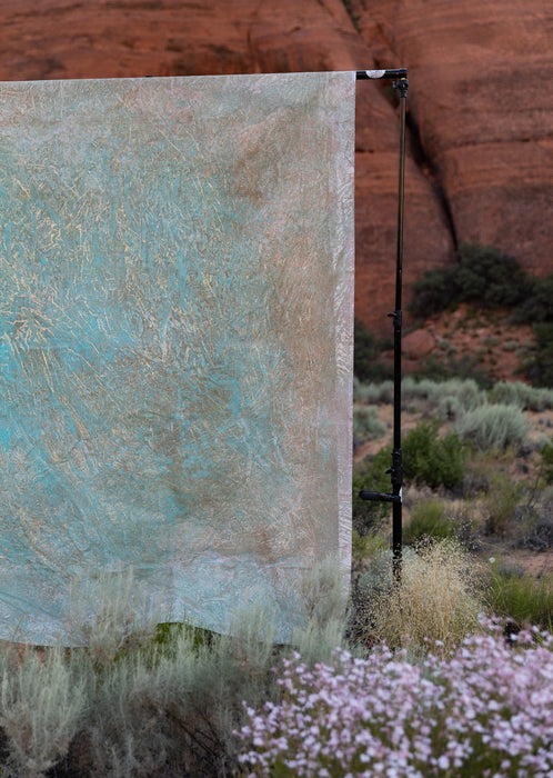 Gold, green and beige hand painted backdrop muslin Backdrop in a Bag by Ultraviolet Backdrops. Image shows desert bloom in Utah's Snow Canyon with sandstone cliffs. Any place indoors or out can be a studio. Backdrop in a Bag rolls up and travels everywhere. 