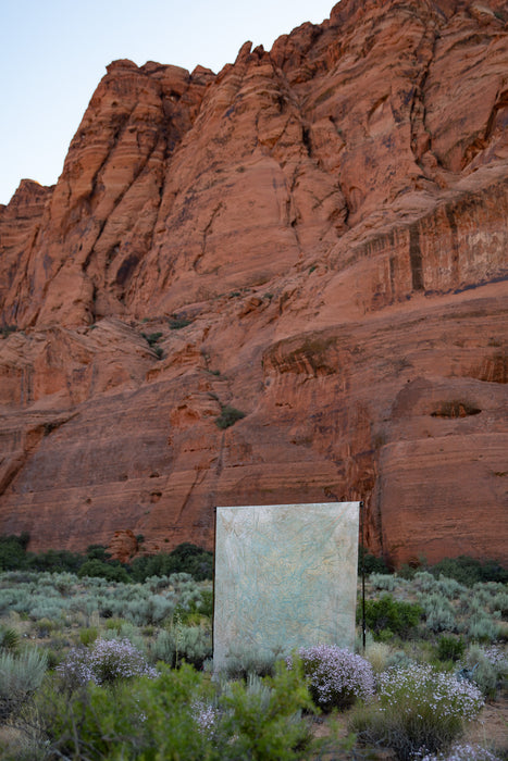 Sandstone cliffs in Utah's Snow Canyon with hand painted Ultraviolet's Backdrop in a Bag installed on a traditional backdrop stand. This large muslin backdrop is one of a kind and travel friendly. 