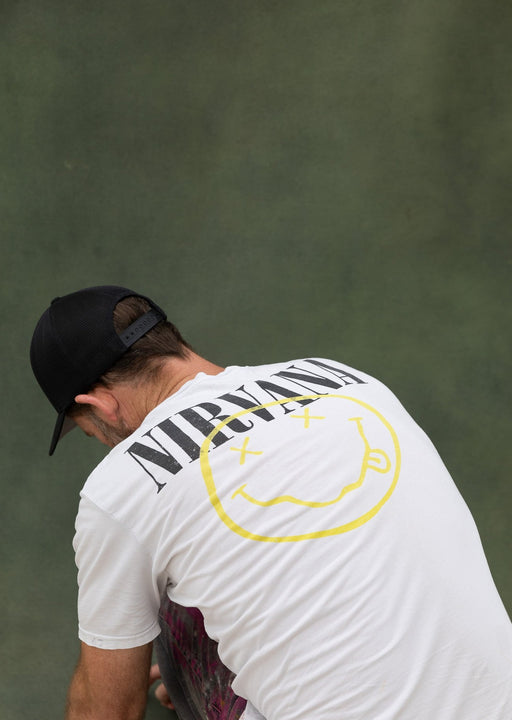 Man in Nirvana tee hunches to straighten hand painted backdrop