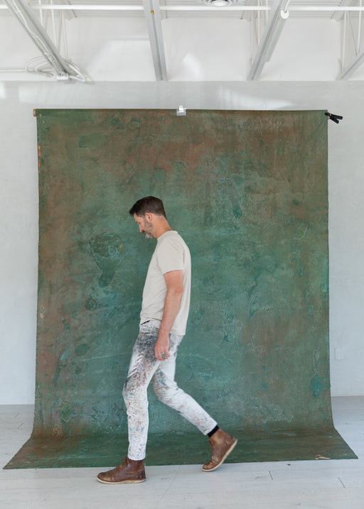 Matthew Peterson of Ultraviolet Backdrops walks in front of an emerald 8'x12' hand painted backdrop.