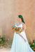 Bride stands against a yellow and pink backdrop with flowers