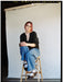 girl with pink hair sits on stool in front of white ultraviolet backdrop