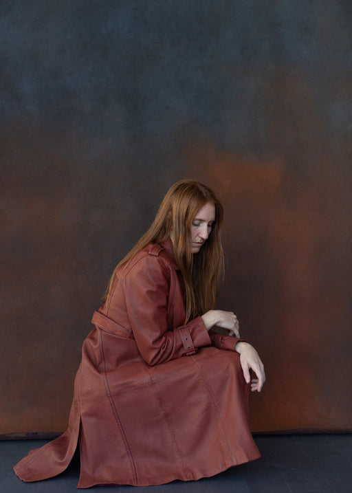 woman poses in front of blue and rust ultraviolet backdrop