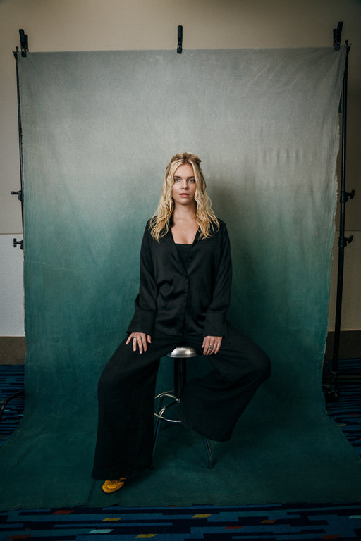 teal gradient backdrop on backdrop stand with woman in black suit on stool