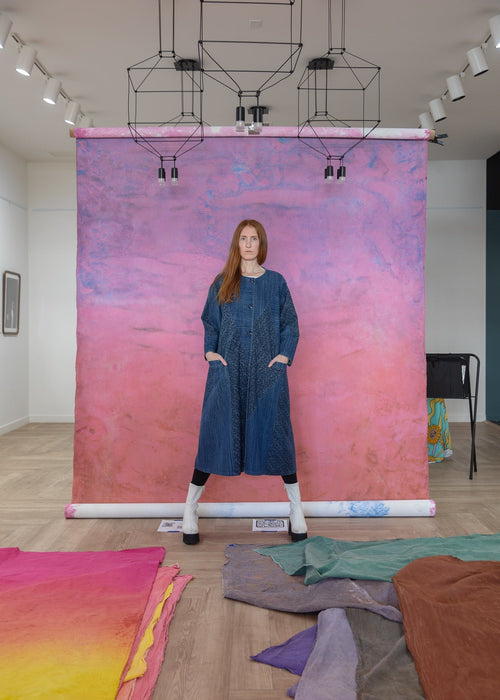 Woman in front of pink orange and blue hand painted Ultraviolet Backdrop